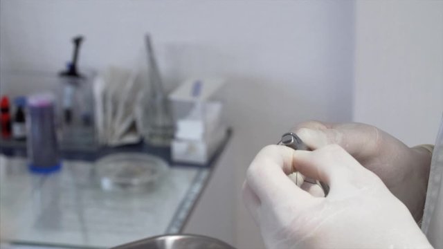 Orthodontist's hands who is preparing the arch wire for patient's braces. A tray with dental instruments. Dental clinic