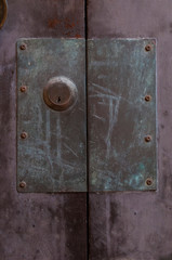 Old door lock with large metal plate on purple wood door