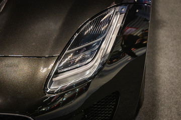 Close up of detail on one of the LED headlights modern and luxury brown car. Select focus.