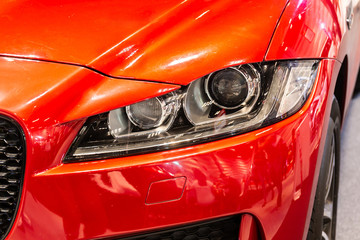 Close up of detail on one of the LED headlights modern and luxury red car. Select focus.