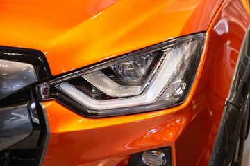 Close up of detail on one of the LED headlights modern and luxury orange car. Select focus.