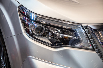 Close up of detail on one of the LED headlights modern and luxury metallic silver car. Select focus.