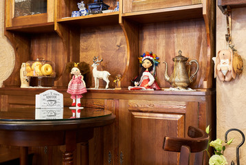 Fragment of cozy interior of a vintage cafe with brown oak wooden tables and chairs and textile toys