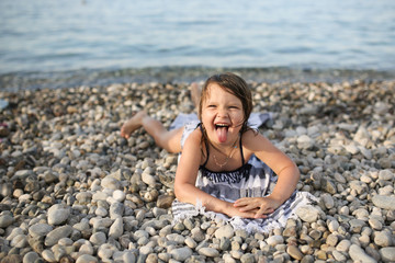 joyful girl child on a towel by the sea