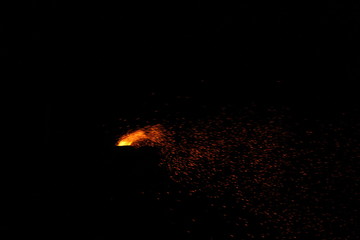 Fototapeta na wymiar Corn being cooked on coal near beach with some fire spark . A corn roaster sparkling fire in the shores of Marina Beach, Chennai, India on night