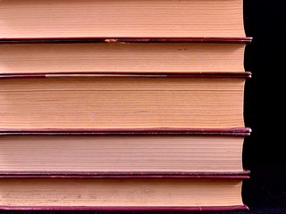 A stack of old hardcover textbooks, on a black background. Thick Books are stacked in a row. Concept: education, training, love of knowledge.