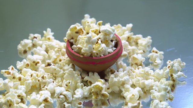 rotating loop shot of popcorn in a mini mud bowl on a reflective background 4K