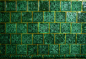 The wall is decorated with tiles, dark green in color with a complex ornament. In the center of the ornament, the tile is different from all the others.