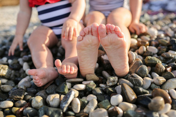 Caucasian sisters in swimsuits by sea on pebble