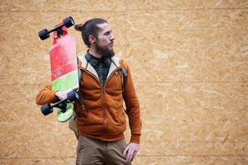 young man with beard and gauged pierced ears holding a skateboard