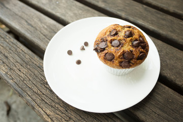 Banana cup cake with chocolate chip topping in white plate. Fresh banana cup cake in foil cup.