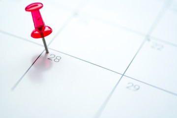 Red push pin on calendar 28th day of the month