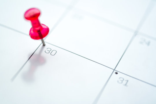 Red push pin on calendar 30th day of the month