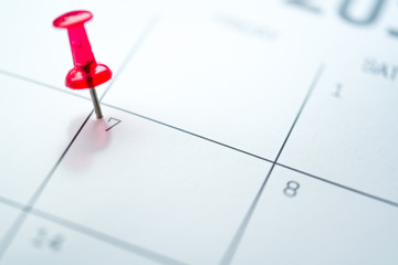 Red push pin on calendar 7th day of the month