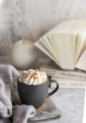 Cozy home concept. Mug of hot chocolate , candle, book and wool sweater.  Winter relax mood and hygge background.