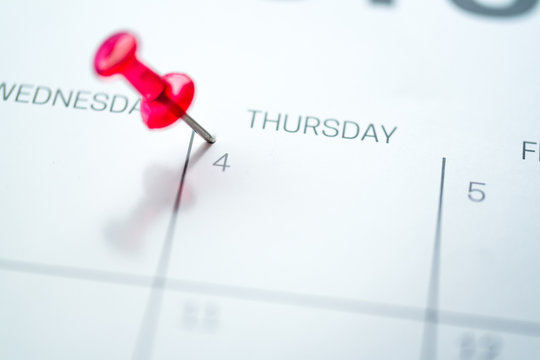 Red push pin on calendar 4th day of the month