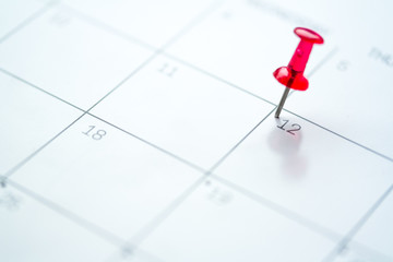 Red push pin on calendar 12th day of the month