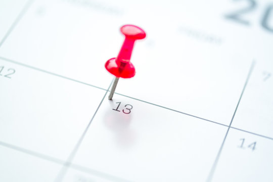 Red push pin on calendar 13th day of the month