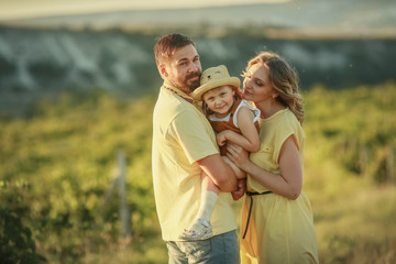 Happy loving family. Husband wife and child at sunset in a grape field.