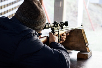 man takes aim at a rifle at a shooting range