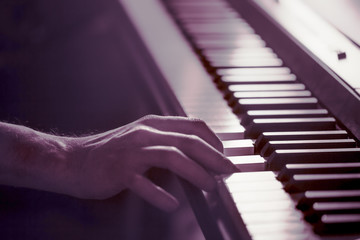 male hands on the piano keys closeup of a beautiful colorful background