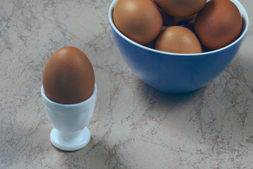 fresh chicken eggs in ceramic cups on a wooden background. Healthy eating concept