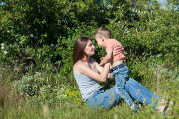 Fototapeta premium Beautiful mom with her son on a picnic rest in nature