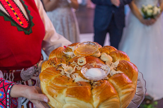 a girl in folk costume holds a cake with honey and salt in her hands.a traditional welcome with bread and salt in Bulgaria.