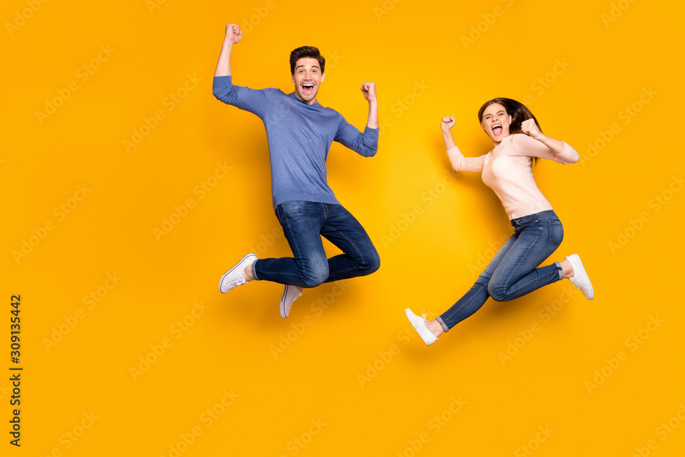 Poster Yeah we winners. Portrait of delighted two married people celebrate lottery victory jump raise fists scream wear casual style outfit sneakers isolated over yellow color background