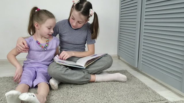 two sisters reading a book in the room