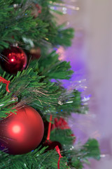 Christmas green spruce with red balls, beads and flowers. Close-up. Soft focus. Christmas and New Year concept.