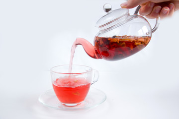 The process of pouring from a teapot into a glass mug of fruit tea.