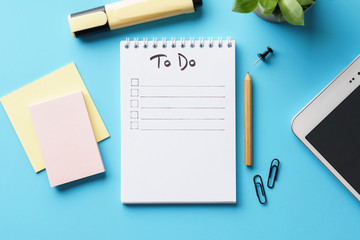 A notebook with to-do list on a blue desk with stationery. - obrazy, fototapety, plakaty