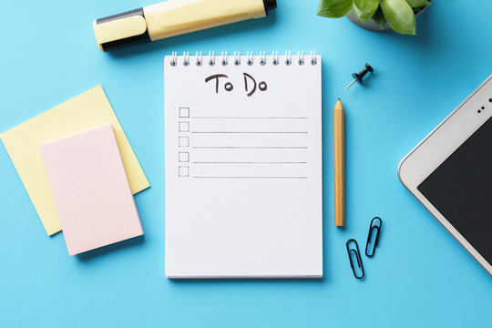 A notebook with to-do list on a blue desk with stationery.