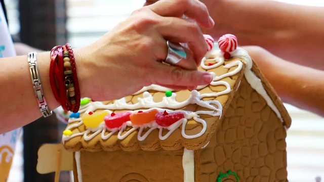 Gingerbread house kit, adding candies on the roof. Costco gingerbread house building for Christmas fun activities.