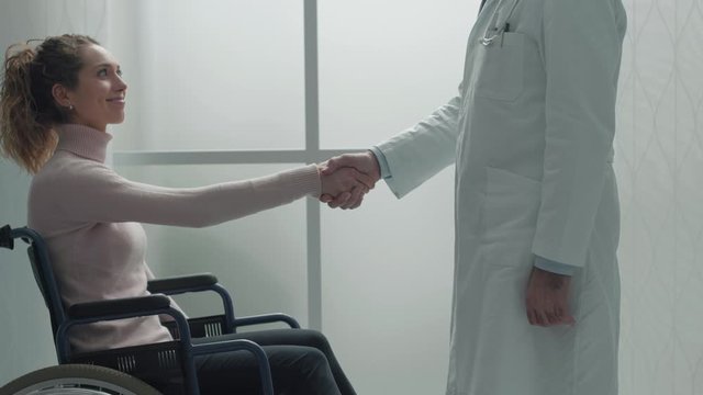 Doctor shaking hand with a disabled patient at hospital