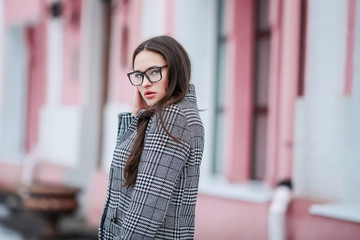 Stylish woman model in a coat walking alone in winter on the streets of the city.