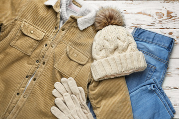 Stylish winter clothes on white wooden background