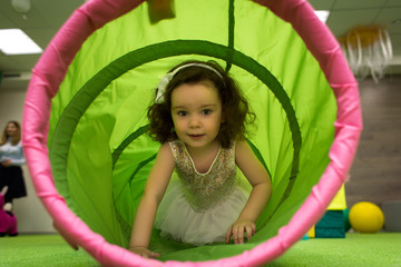 little girl crawls inside toy tunnel at childrens holiday