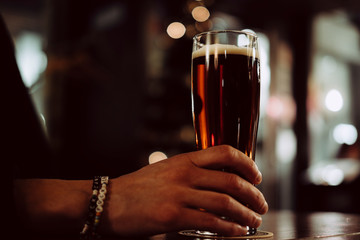 Closeup of hand holding beer in a bar in Berlin