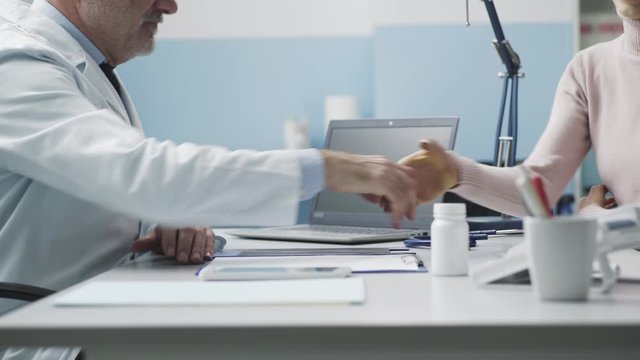 Professional doctor and patient giving a handshake in the office