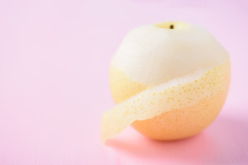 Fresh Asian pear fruit peeling on pink background
