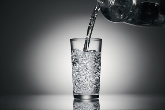 pouring sparkling water in a glass on a dark background