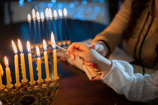 jewish holiday Chanukah/Hanukkah family selebration. Jewish festival of lights. Children lighting candles on traditional menorah over glitter shiny background
