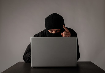 Hacker in mask using a laptop.