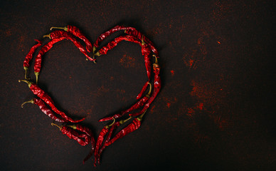 Hot dry red pepper over black background. Chilli pepper heart
