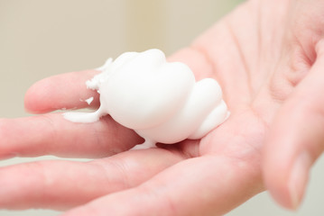 Shaving foam on a female palm of hand close up background.