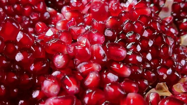 Cloce up of a shining juicy grains of red pomegranate are falling down
