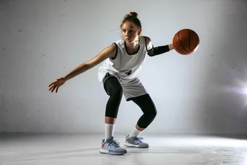 Fotobehang Young caucasian female basketball player of team in action, motion in run isolated on white wall background. Concept of sport, movement, energy and dynamic, healthy lifestyle. Training, practicing. © master1305