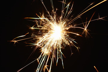 Christmas and New Year's illumination. Burning sparklers scatter bright exploding strips of sparks on a dark background.